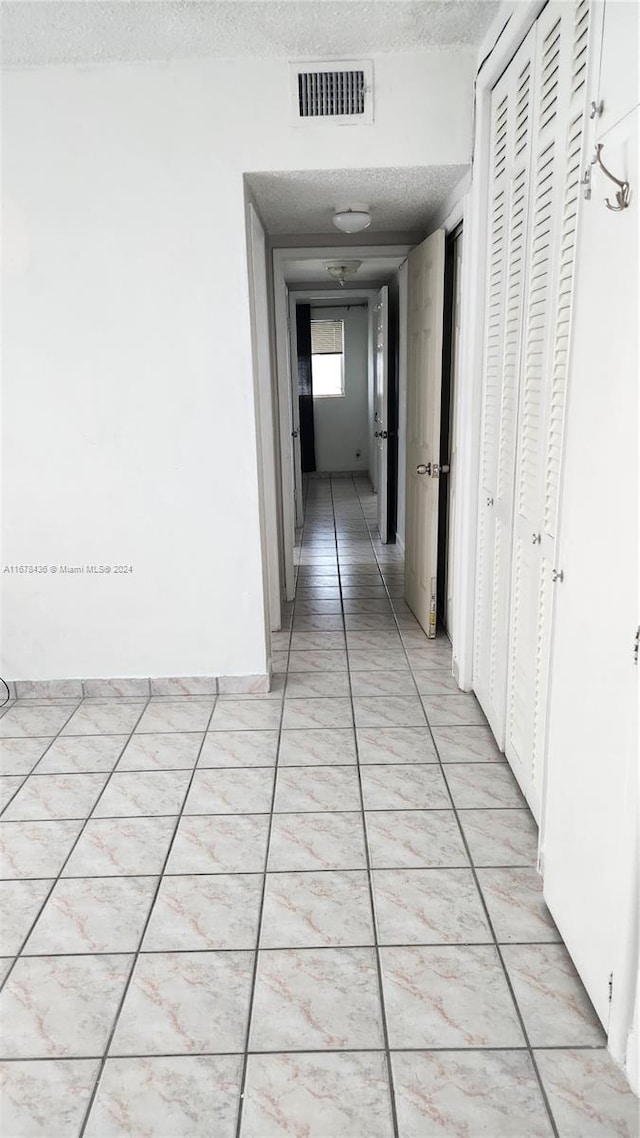 corridor with a textured ceiling and light tile patterned floors