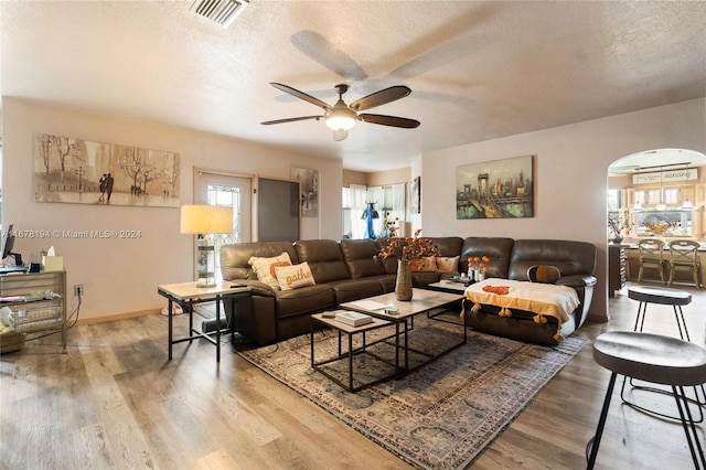 living room with a textured ceiling, hardwood / wood-style floors, and ceiling fan