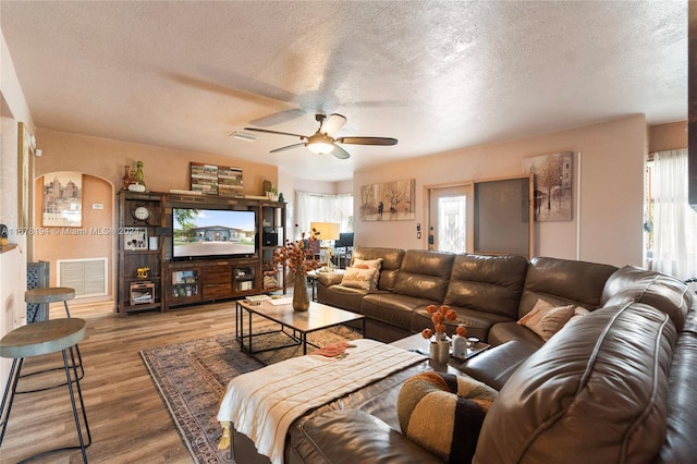 living room featuring ceiling fan, hardwood / wood-style flooring, a textured ceiling, and a wealth of natural light