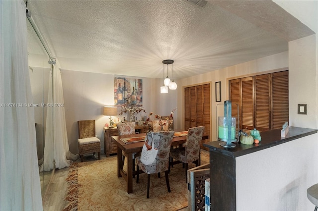 dining room with a textured ceiling and hardwood / wood-style floors