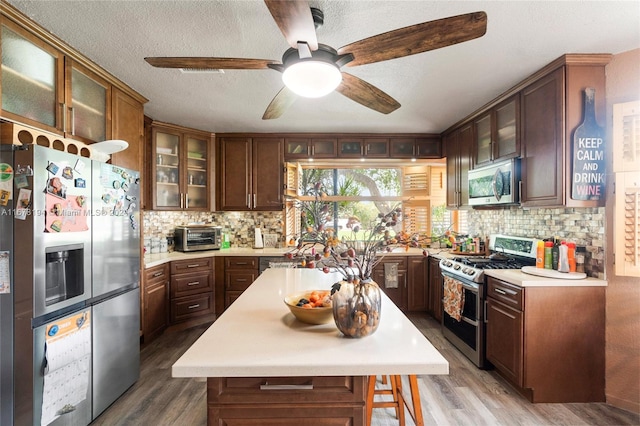 kitchen with a kitchen island, stainless steel appliances, backsplash, and hardwood / wood-style flooring