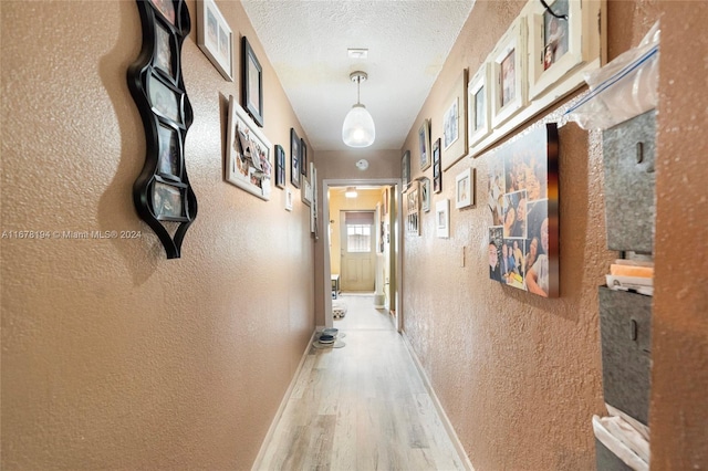 corridor with a textured ceiling and hardwood / wood-style flooring