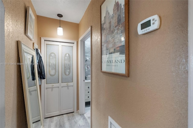 hallway with a textured ceiling and light hardwood / wood-style floors