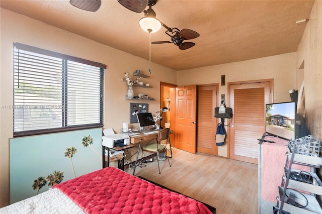 bedroom with a textured ceiling, light wood-type flooring, and ceiling fan