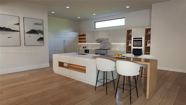 kitchen featuring stainless steel appliances, sink, light wood-type flooring, and a kitchen breakfast bar