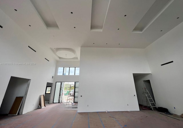 unfurnished living room featuring a towering ceiling