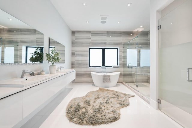 bathroom with vanity, independent shower and bath, tile walls, and a wealth of natural light