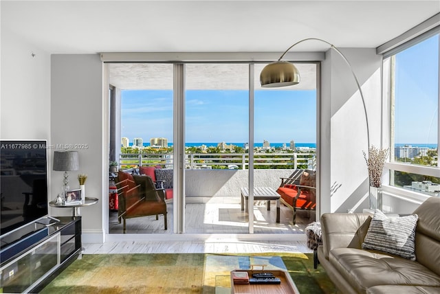 living area featuring a city view, a wall of windows, plenty of natural light, and a water view