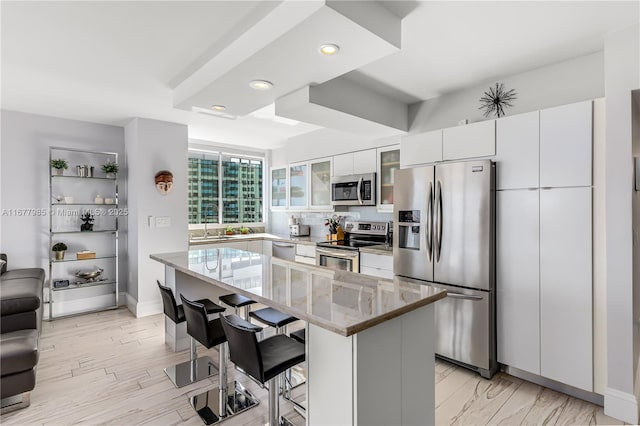 kitchen featuring a breakfast bar, sink, white cabinets, a center island, and stainless steel appliances