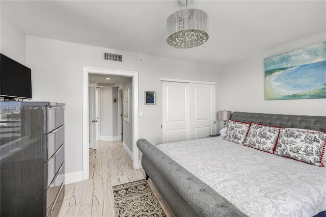 bedroom featuring a chandelier, multiple windows, and light wood-type flooring