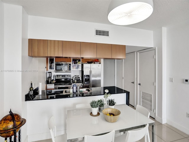 kitchen featuring a textured ceiling, light tile patterned flooring, and stainless steel appliances