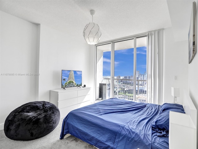 carpeted bedroom featuring access to outside, a textured ceiling, and floor to ceiling windows