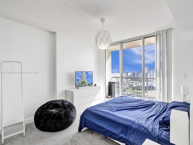 bedroom featuring carpet, a wall of windows, access to exterior, and a textured ceiling