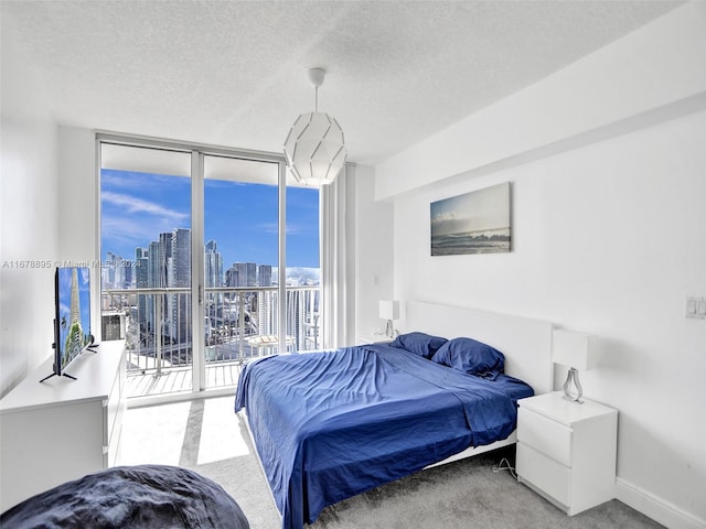 carpeted bedroom with a textured ceiling, access to exterior, and floor to ceiling windows