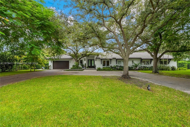 ranch-style home with a garage and a front lawn