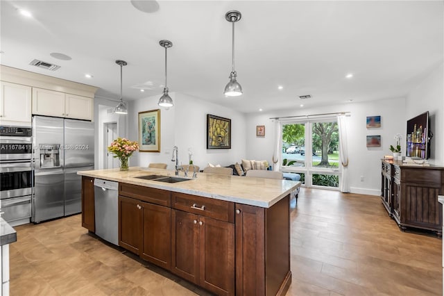 kitchen with appliances with stainless steel finishes, sink, light hardwood / wood-style floors, and pendant lighting