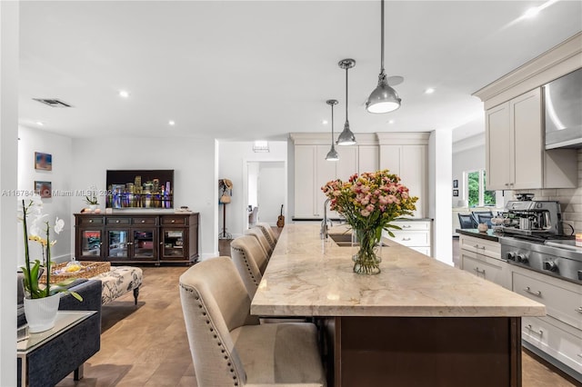 kitchen with tasteful backsplash, a kitchen island, stainless steel gas cooktop, decorative light fixtures, and light stone counters