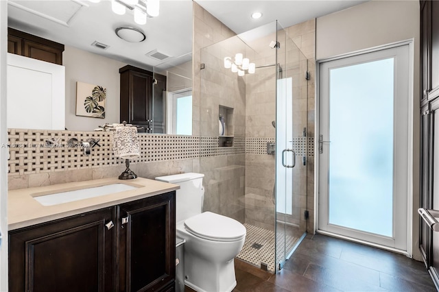 bathroom featuring a shower with door, toilet, vanity, decorative backsplash, and tile patterned flooring