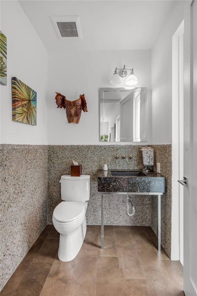 bathroom featuring toilet, tile patterned floors, tile walls, and sink