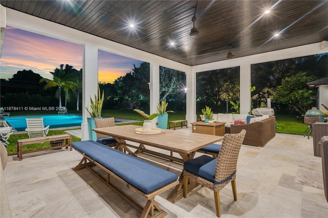 patio terrace at dusk with ceiling fan, an outdoor hangout area, and a grill