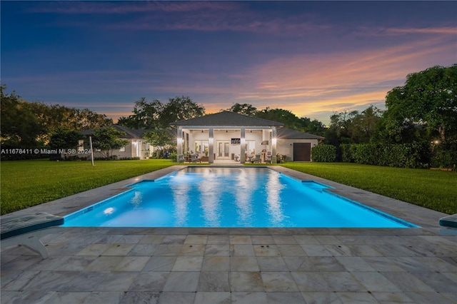 pool at dusk featuring a yard and a patio area