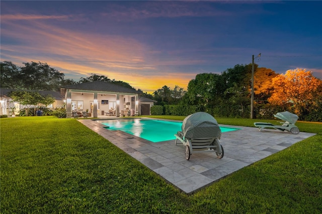 pool at dusk with a patio and a lawn