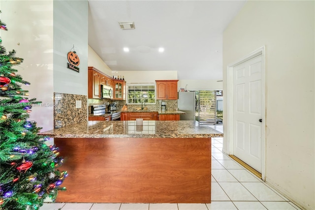 kitchen with kitchen peninsula, decorative backsplash, light tile patterned floors, and stainless steel appliances