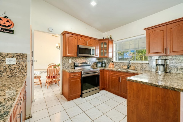 kitchen featuring sink, vaulted ceiling, light tile patterned floors, stone countertops, and stainless steel appliances