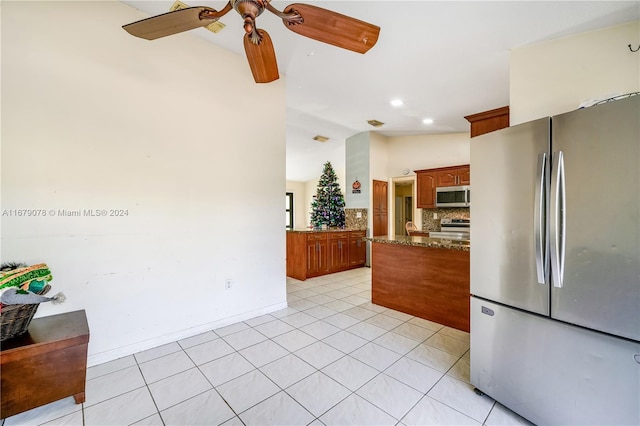 kitchen with appliances with stainless steel finishes, backsplash, ceiling fan, light tile patterned floors, and dark stone countertops