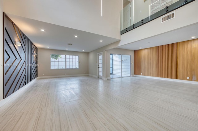 unfurnished room featuring wooden walls and a high ceiling