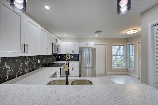 kitchen with decorative backsplash, stainless steel appliances, sink, light stone countertops, and white cabinets