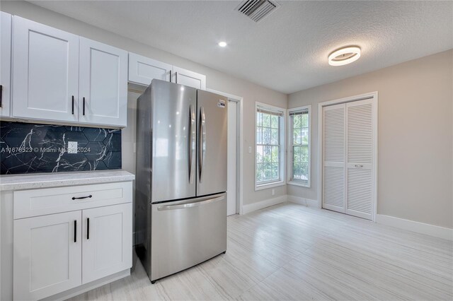 115 Ocean Dunes Cir, Jupiter, FL 33477 - kitchen featuring freestanding refrigerator, light countertops, tasteful backsplash, baseboards, and white cabinets