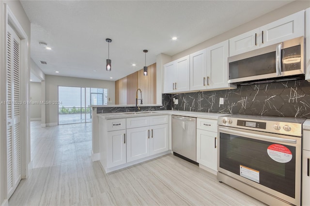 kitchen with sink, stainless steel appliances, pendant lighting, white cabinets, and decorative backsplash