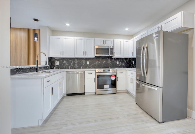 kitchen featuring stainless steel appliances, sink, decorative light fixtures, white cabinetry, and tasteful backsplash