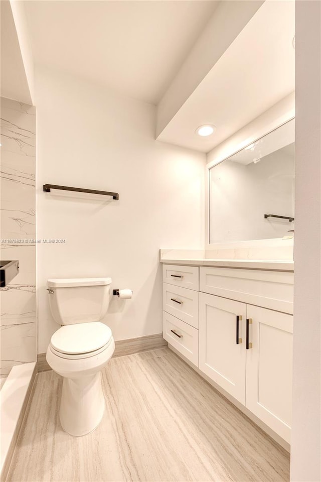 bathroom with vanity, toilet, and hardwood / wood-style flooring