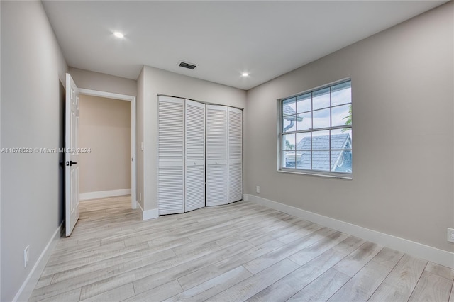 unfurnished bedroom with light hardwood / wood-style flooring and a closet