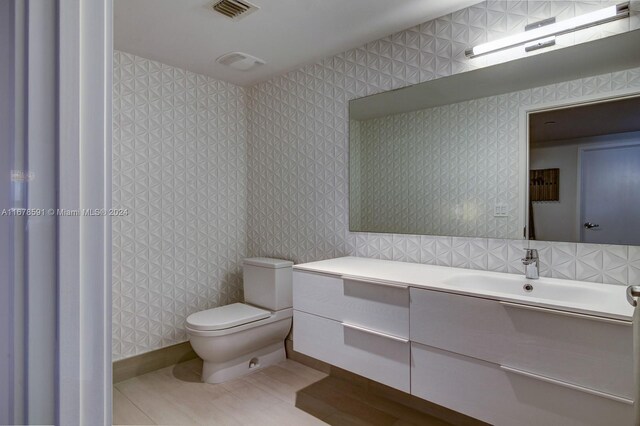 9940 W Bay Harbor Dr Unit 7G-N, Bay Harbor Islands, FL 33154 - bathroom with toilet, vanity, wallpapered walls, and tile patterned flooring