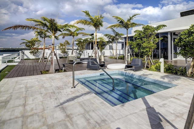 view of swimming pool featuring a patio, a deck with water view, and an in ground hot tub