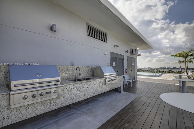 deck with area for grilling, a wall mounted AC, sink, and grilling area