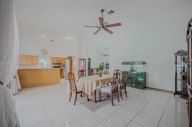 tiled dining space featuring ceiling fan and a towering ceiling