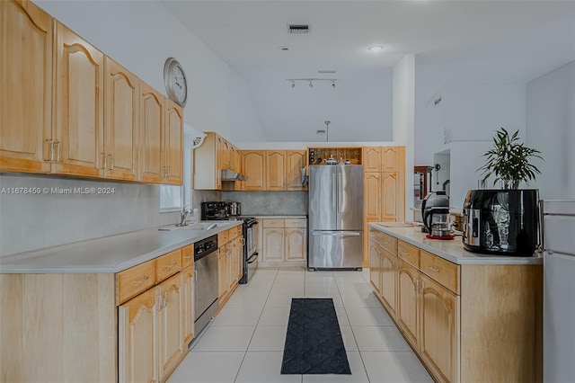 kitchen with light brown cabinetry, sink, stainless steel appliances, lofted ceiling, and light tile patterned floors