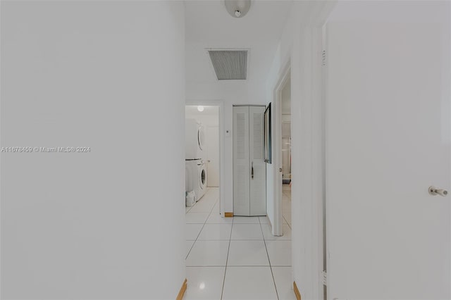 hall featuring stacked washing maching and dryer and light tile patterned floors