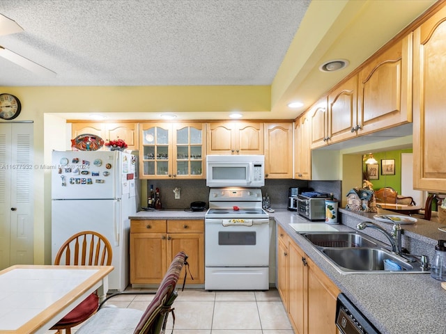 kitchen with light brown cabinets, sink, light tile patterned floors, a textured ceiling, and white appliances