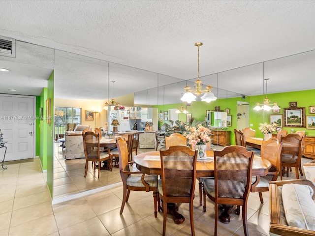 tiled dining space with a textured ceiling and a chandelier