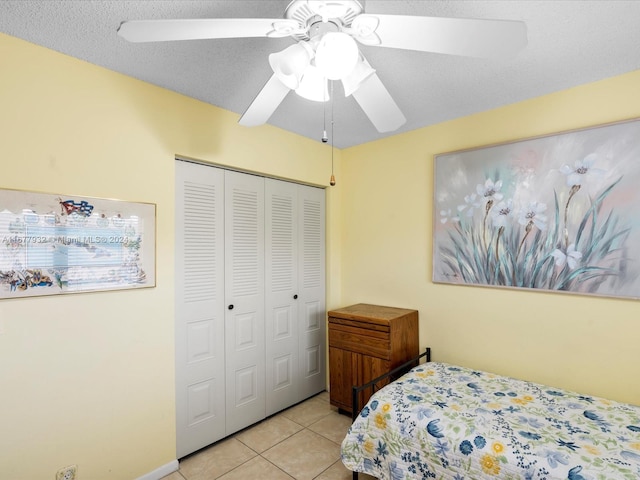 tiled bedroom with a closet, ceiling fan, and a textured ceiling