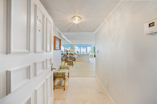 hall with ornamental molding, a textured ceiling, and light colored carpet