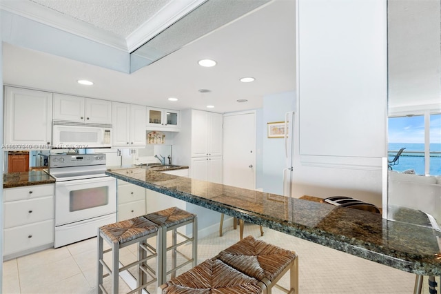 kitchen featuring a kitchen breakfast bar, white cabinetry, a water view, and white appliances