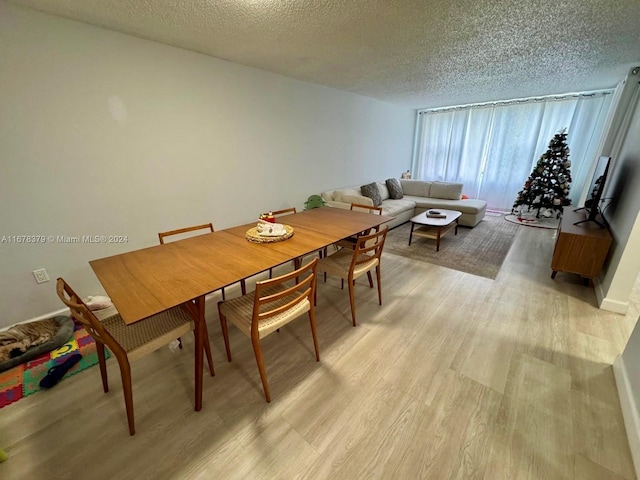 dining room with light wood-type flooring and a textured ceiling