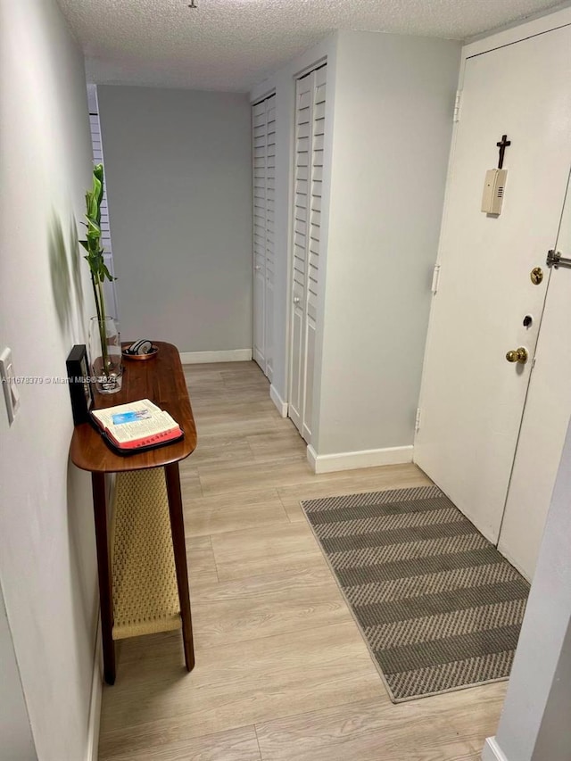 corridor with light hardwood / wood-style floors and a textured ceiling