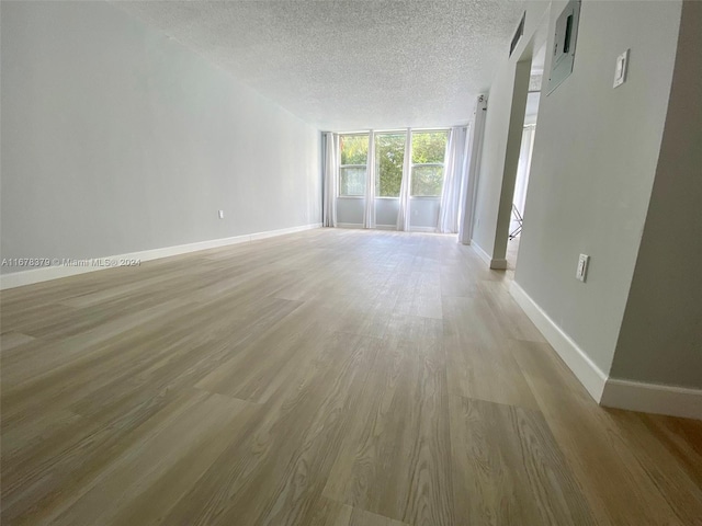 spare room with a textured ceiling and light hardwood / wood-style flooring